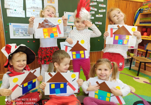 Dzieci pokazują swoją pracę plastyczną. Z gotowych figur ułożony i przyklejony domek a na nim flaga biało-czerwona.